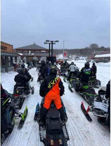 In a now viral photo, snowmobilers wait for gas outside Bayshore Market in Grand Marais.