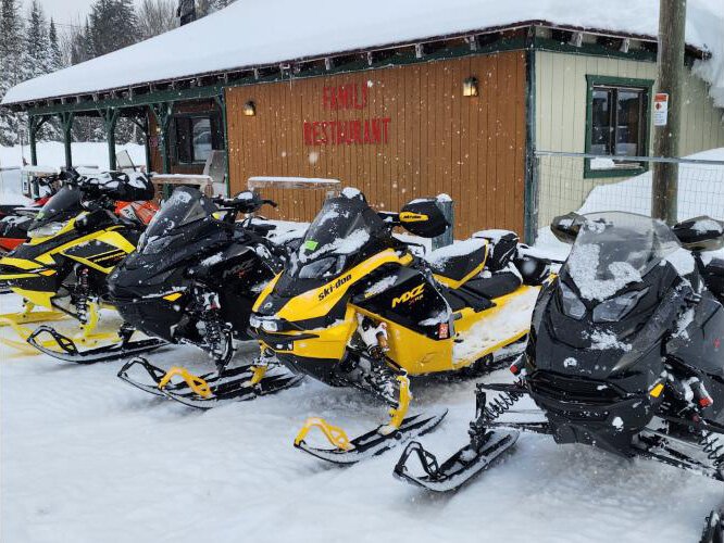 Snowmobiles line up outside the Bear Trap restaurant in Van Meer,