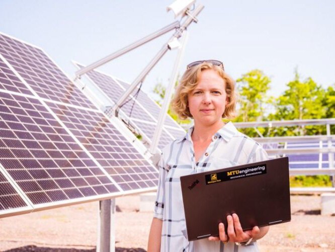 Ana Dyreson in front of solar panels, without snow. 