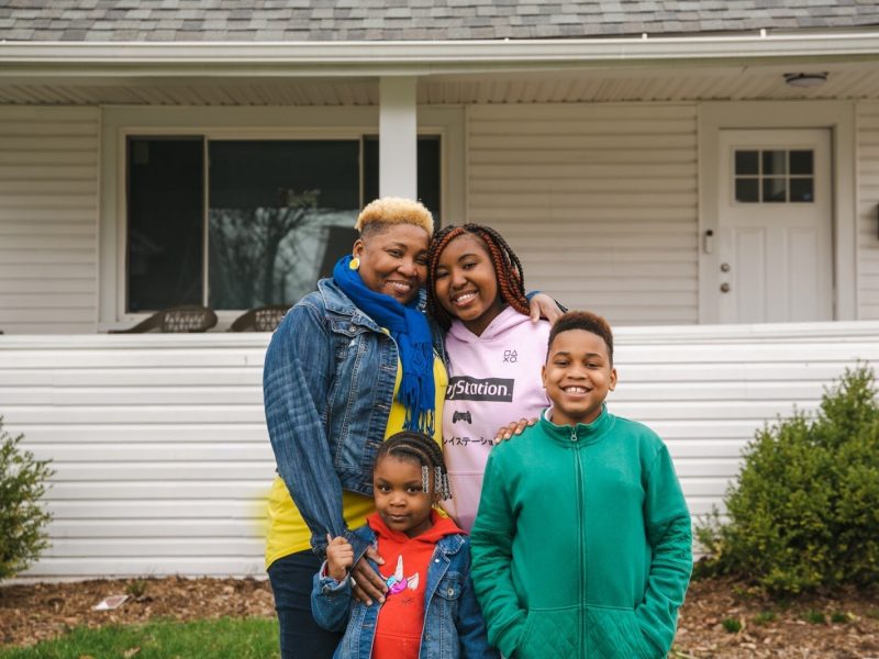 A family poses in front of their ICCF community land trust home.